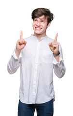 Young handsome business man over isolated background amazed and surprised looking up and pointing with fingers and raised arms.