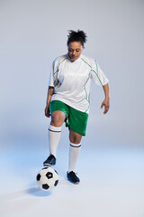 Female athlete in white jersey, green shorts practices footwork with soccer ball.