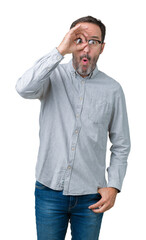 Fototapeta premium Handsome middle age elegant senior man wearing glasses over isolated background doing ok gesture shocked with surprised face, eye looking through fingers. Unbelieving expression.