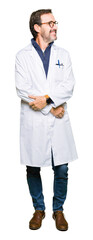 Middle age therapist wearing white coat looking away to side with smile on face, natural expression. Laughing confident.