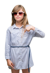 Young blonde toddler wearing blue shirt with surprise face pointing finger to himself