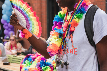 Black man with rainbow fan and colorful accessories at nottingham pride festival, celebrating lgbtq community with festive parade, candid shot Nottingham, UK
