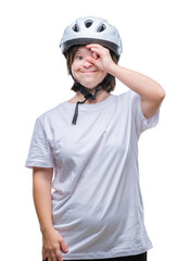 Young adult cyclist woman with down syndrome wearing safety helmet over isolated background doing ok gesture with hand smiling, eye looking through fingers with happy face.