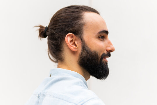 Profile view of a bearded young man against a plain background