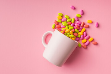 Colorful hard mint Candies in cup on pink background. Top view.