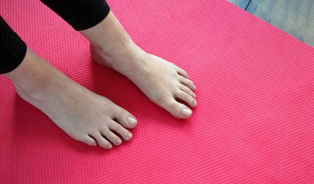Pies hermosos y saludables de mujer joven con pedicura de aspecto natural sobre mat o esterilla. 