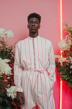 Fashion model in striped jumpsuit against a pink floral backdrop. Generative AI image