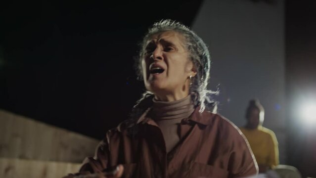 Senior actress holding paper script and showing emotional performance on stage during rehearsal in theatre