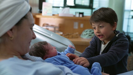Bonding family moment of sibling interacting with his newborn baby brother at hospital after...