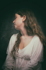 long-haired young woman in antique white dress sitting on a chair in a melancholic attitude II