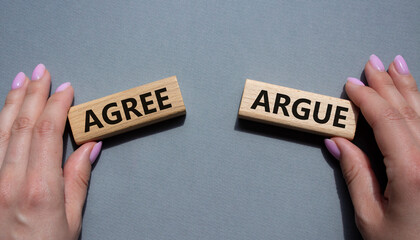 Agree or Argue symbol. Concept word Agree or Argue on wooden blocks. Businessman hand. Beautiful green background. Gender and Agree or Argue concept. Copy space