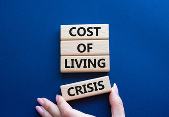 Cost of Living Crisis symbol. Wooden blocks with words Cost of Living Crisis. Businessman hand....