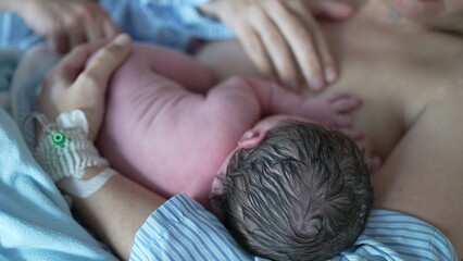 Newborn baby breastfeeding for the first time right after birth emphasizing skin to skin contact....