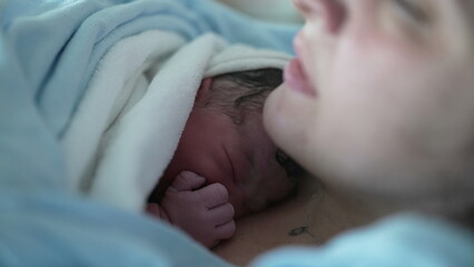 Newborn baby resting on mother's chest right after birth emphasizing skin to skin contact, real...