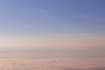 Morning view over white puffy clouds with blue sky on horizon.