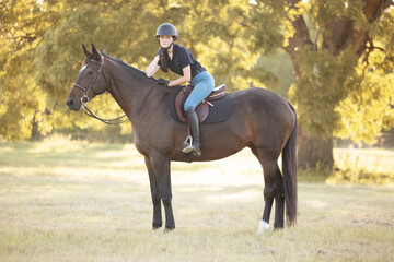 Young equestrian girl woman with horse equine in english tack and riding attire hunter jumper