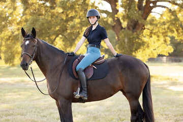 Young equestrian girl woman with horse equine in english tack and riding attire hunter jumper
