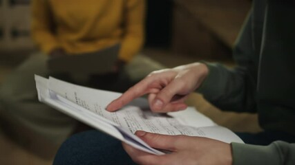 Close up shot of hands of unrecognizable actor reading play script printed on paper while learning his monologue on theatre rehearsal