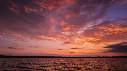 sunset over a tranquil lake with rippled water, sky with soft clouds