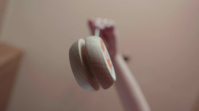 Childs hand spinning a wooden yo-yo toy, shot in a slow-motion, from low-angle close-up perspective.