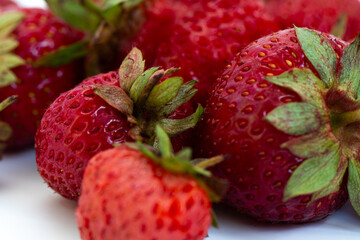 Fresh ripe natural strawberries on a white background. Freshly picked garden strawberries. Detailed photo of strawberries on an abstract background. Close up view.