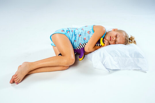 Cute preteen girl in floral pajamas asleep on a pillow while hugging her stuffed animal toy