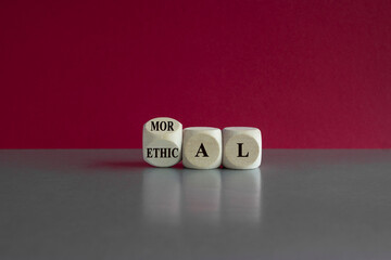 Ethical or moral symbol. Turned a wooden cube and changes the word 'moral' to 'ethical' on a beautiful gray table, pink background. Business and ethical or moral concept.