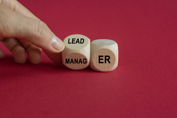 Manager versus leader symbol. Businessman flips a wooden cube and changes the word 'manager' to 'leader'. Beautiful red background, copy space. Business and manager versus leader concept.