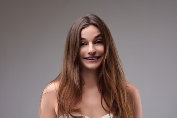 Naklejka premium Beautiful young woman with long brown hair smiling on grey backg