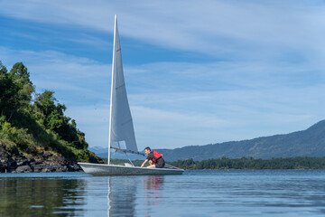 Fototapeta premium Teenager sailing on a beautiful summer day on the lake. laser sail boat