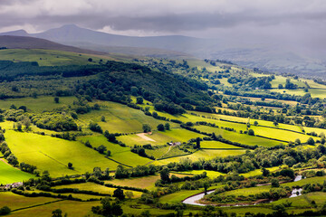 Rain falling over lush, green farmland and hills © whitcomberd