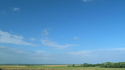 Wild nature and rural pasture field. Clouds swim around sky. White clouds floating to distance in blue sky. Timelapse.