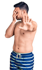 Naklejka premium Young handsome man wearing swimwear covering eyes with hands and doing stop gesture with sad and fear expression. embarrassed and negative concept.