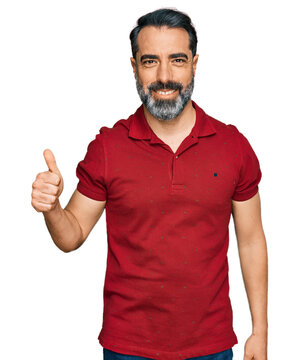Middle aged man with beard wearing casual red t shirt smiling happy and positive, thumb up doing excellent and approval sign