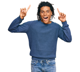 Young african american man wearing casual winter sweater smiling amazed and surprised and pointing up with fingers and raised arms.