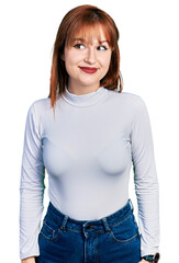 Redhead young woman wearing casual turtleneck sweater smiling looking to the side and staring away thinking.