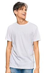 Obraz premium Young hispanic man wearing casual white tshirt looking away to side with smile on face, natural expression. laughing confident.