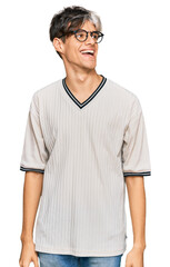 Obraz premium Young hispanic man wearing casual clothes and glasses looking away to side with smile on face, natural expression. laughing confident.