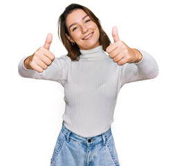 Young caucasian girl wearing casual clothes approving doing positive gesture with hand, thumbs up smiling and happy for success. winner gesture.