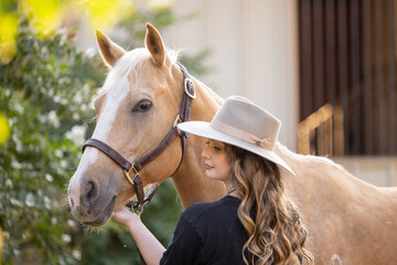 Cowgirl with Palomino Quarter Horse during Golden hour