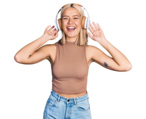 Beautiful young blonde woman listening to music using headphones smiling and laughing hard out loud because funny crazy joke.