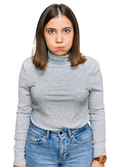 Obraz premium Young beautiful woman wearing casual turtleneck sweater puffing cheeks with funny face. mouth inflated with air, crazy expression.