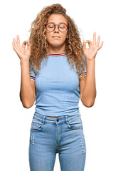 Beautiful caucasian teenager girl wearing casual clothes and glasses relax and smiling with eyes closed doing meditation gesture with fingers. yoga concept.