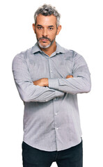 Middle age grey-haired man wearing casual clothes skeptic and nervous, disapproving expression on face with crossed arms. negative person.