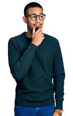 Young african american man wearing casual clothes and glasses with hand on chin thinking about question, pensive expression. smiling with thoughtful face. doubt concept.