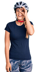 Beautiful caucasian woman wearing bike helmet doing ok gesture with hand smiling, eye looking through fingers with happy face.