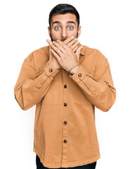 Young hispanic man wearing casual clothes shocked covering mouth with hands for mistake. secret concept.