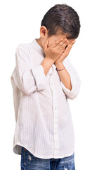 Cute blond kid wearing elegant shirt with sad expression covering face with hands while crying. depression concept.