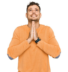 Young hispanic man wearing casual clothes begging and praying with hands together with hope...