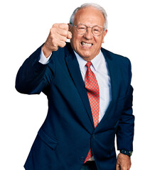 Senior man with grey hair wearing business suit and glasses angry and mad raising fist frustrated...